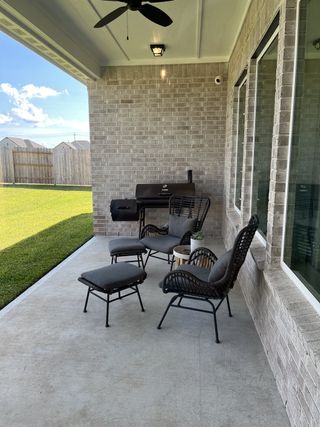 Model Home A cozy patio with stylish wicker chairs, a sleek grill, and lush lawn, perfect for outdoor relaxation and entertainment.