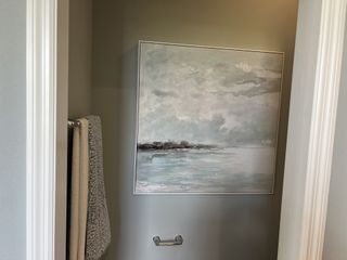 Model Home A serene bathroom nook with abstract coastal artwork, a soft towel, and calming neutral tones.