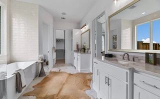 A luxurious bathroom featuring a spacious bathtub, elegant double vanity, and natural light pouring in through large windows.