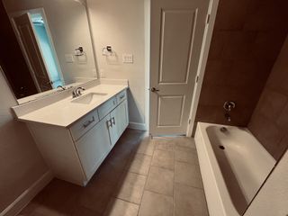 A modern bathroom featuring a sleek vanity, spacious mirror, and a tiled bathtub for a clean, contemporary feel.