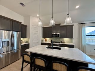 A modern kitchen with sleek cabinetry, a marble island, and pendant lighting.