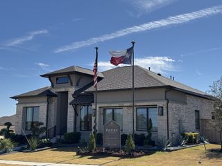 Street view A charming stone home with a well-manicured lawn in Nolina 60' by Perry Homes (Georgetown, TX).