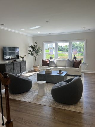 A modern living room with plush seating, a sleek TV console, and abundant natural light through large windows.