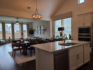 A modern open-concept living space with sleek kitchen, elegant dining area, and large windows, perfect for entertaining.