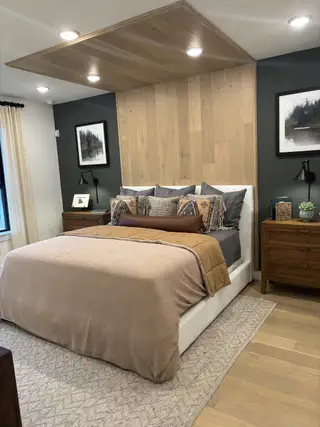 Model Home A cozy bedroom featuring warm wood accents, modern lighting, and plush bedding with stylish decor.