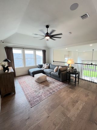 A cozy loft with a plush sectional sofa, striped ottoman, and rustic wood floors, offering a bright and airy retreat.