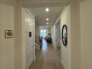 A welcoming hallway with light wood flooring, elegant wall decor, and vibrant natural light highlighting modern interiors.