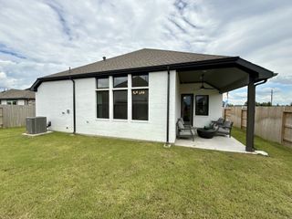 Street view A charming white brick home with a spacious patio in Oakwood Estates by Brightland Homes (Waller, TX).
