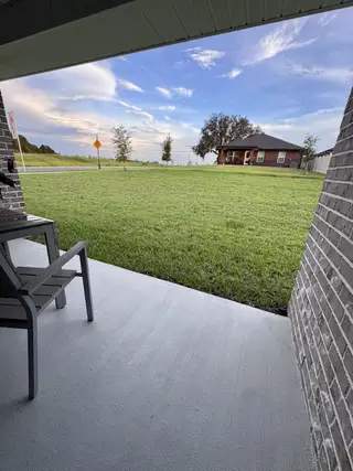 A cozy patio overlooking a vast, green lawn under a scenic sky in Shadow Crest at Rolling Hills by Adams Homes (Green Cove Springs, FL).
