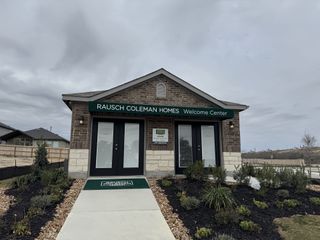 A welcoming brick and stone center with greenery in Hunters Ranch by Rausch Coleman Homes (San Antonio, TX).