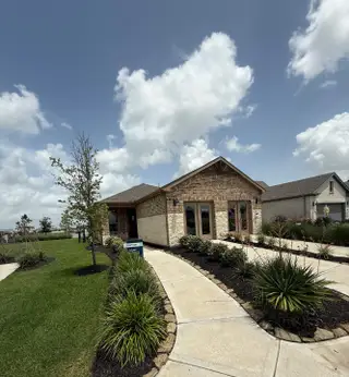 Street view A charming brick home with manicured landscaping in Del Webb Fulshear by Del Webb (Fulshear, TX).