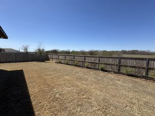 A spacious fenced yard with a clear blue sky in Venado Crossing by Beazer Homes (Cibolo, TX).