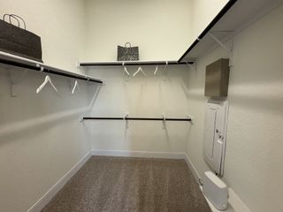 Model Home Spacious walk-in closet with ample hanging space and shelving for effortless organization in Veramendi by Coventry Homes (New Braunfels, TX).