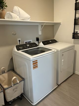 A sleek laundry room featuring modern appliances, a spacious shelf, and a laundry basket on wheels. Perfect for efficient living.