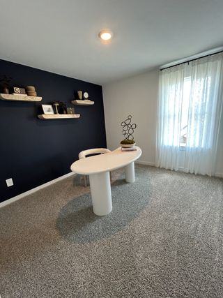 A modern office with a unique oval desk, navy accent wall, and floating shelves creating a sleek, contemporary workspace.