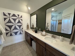 A modern bathroom featuring a marble vanity, sleek cabinetry, geometric wall art, and a spacious shower.