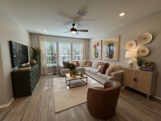 A cozy living room featuring warm tones, elegant decor, large windows, and stylish furniture, perfect for relaxation.
