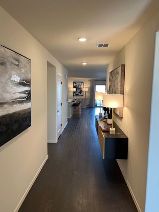 A modern hallway with sleek wooden flooring, elegant wall art, and ambient lighting.