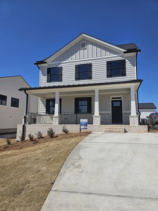 A charming white siding home with rustic shutters and porch in Rose Harbor by Bassett Signature Homes (Flowery Branch, GA).