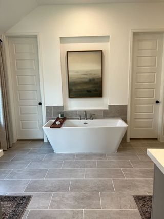 A serene bathroom featuring a sleek freestanding tub, modern decor, and elegant tile flooring.