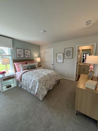 A cozy bedroom featuring floral decor, soft lighting, and plush carpeting.