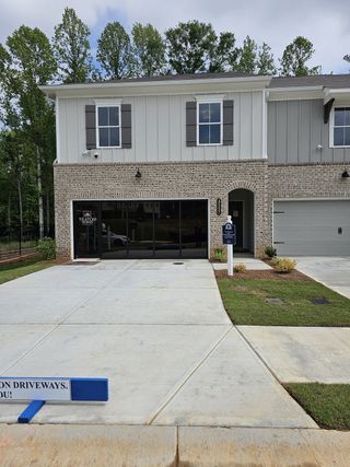 Street view A charming two-story home with a brick facade and manicured lawn in Wildwood Place by Traton Homes (Powder Springs, GA).