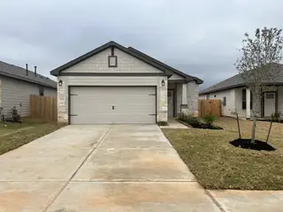 Model Home A beautifully landscaped home with a gray garage and stone accents in Bluestem by First America Homes (Brookshire, TX).