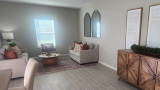 A cozy living room with neutral tones, a stylish wooden sideboard, decorative mirrors, and plush seating.
