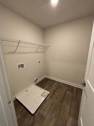 A utility room with wood flooring, open shelving, and plumbing hookups, ready for customization.