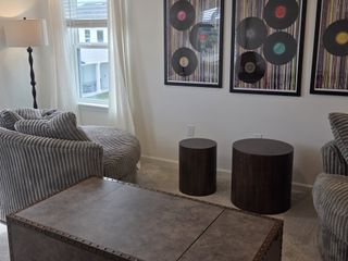 A cozy living area featuring plush gray seating, vintage vinyl artwork, and modern accents.