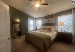 A cozy bedroom featuring a plush bed, elegant wall art, and stylish lighting with a large decorative mirror.