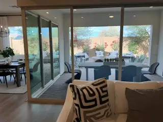 A modern living area with sliding glass doors opening to a stylish patio, creating an airy, seamless indoor-outdoor space.