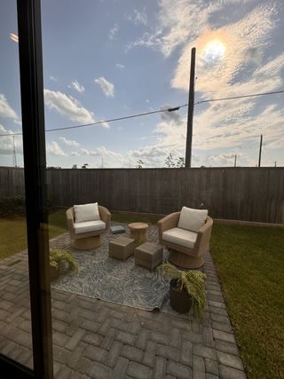Cozy patio with wicker chairs, a patterned rug, and greenery, perfect for relaxing outdoors.