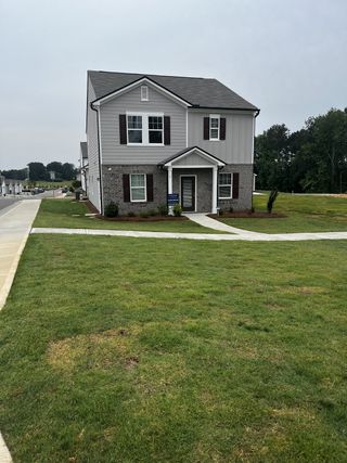 Charming two-story home with a manicured lawn in the Casteel community by Starlight Homes (Bethlehem, GA).