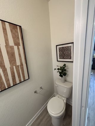 A cozy bathroom corner with modern art, a sleek toilet, and stylish decor on laminate flooring.