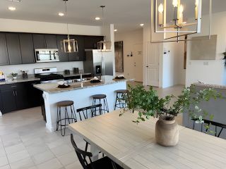Model Home A modern kitchen and dining area with dark cabinets, sleek lighting, and a large island for casual seating.