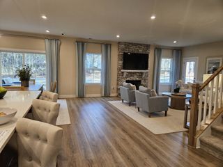 A cozy living area with wood floors, stone fireplace, and ample natural light, complemented by elegant neutral furnishings.