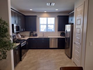 A modern kitchen featuring dark wood cabinets, stainless steel appliances, and a bright window for natural light.