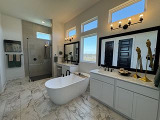 A luxurious bathroom featuring a freestanding tub, marble tiles, a large mirror, and chic lighting.