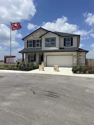 A beautiful stone-accented home with a two-car garage and landscaped yard in Red Hawk Landing by CastleRock Communities (San Antonio, TX).