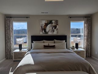 Model Home A spacious master bedroom with a feature wall, large windows, and cozy neutral decor in Red Hawk Landing by HistoryMaker Homes (San Antonio, TX).