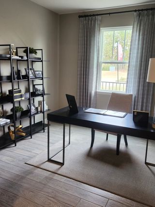 A sophisticated home office featuring a sleek black desk, modern shelving, and a large window with elegant curtains.