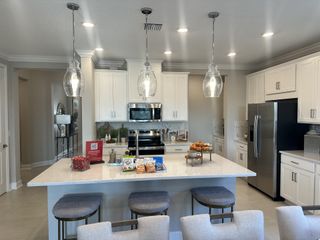A modern kitchen with white cabinets, stainless steel appliances, and pendant lighting over a spacious island.