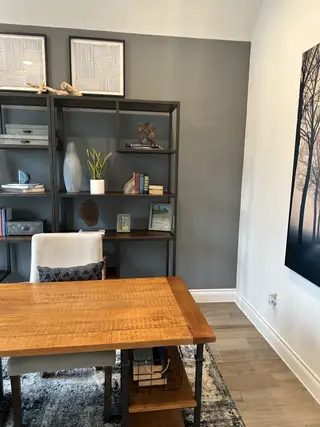 A modern office with a wooden desk, sleek shelving, and contemporary decor accents.