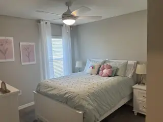A cozy bedroom with a soft palette, floral decor, and a stylish ceiling fan for a comfortable retreat.