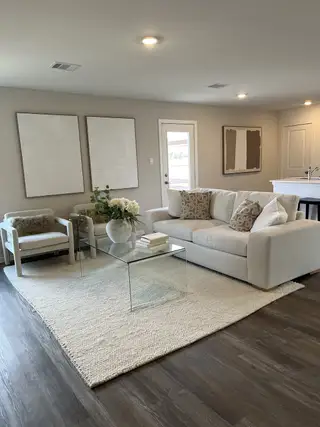 Modern living room with neutral tones, glass coffee table, and plush seating creating a cozy atmosphere.