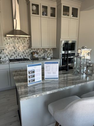 Model Home A modern kitchen with sleek cabinetry, patterned backsplash, and a stylish granite island complemented by elegant decor.