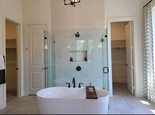 Model Home A luxurious bathroom with a freestanding tub, glass shower, and elegant, neutral-toned walls.