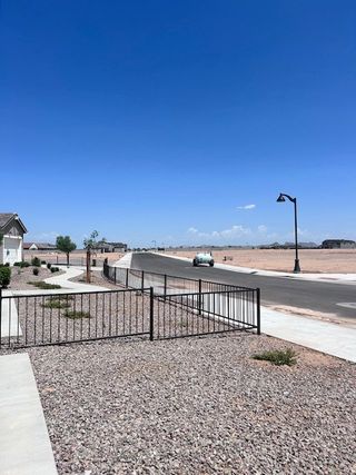 Street view A developing neighborhood with wide streets and desert landscaping in Estates at Rancho Mirage by K. Hovnanian® Homes (Maricopa, AZ).