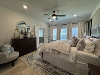 Model Home A cozy bedroom with soft lighting, a plush bed, elegant dresser, and large windows for natural light.